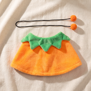 The orange side of the cape laid flat with its cord and pom-poms