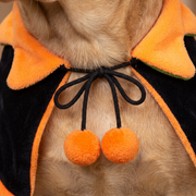 Close-up of the cape fastening, black cord tied in a bow with two orange pom-poms