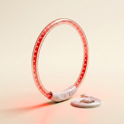The glow collar standing upright on a warm ivory studio backdrop, LED points lit red, USB cable coiled beside it