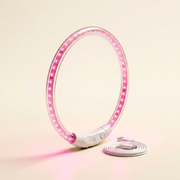 The glow collar standing upright on a warm ivory studio backdrop, LED points lit pink, USB cable coiled beside it