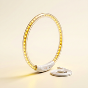 The glow collar standing upright on a warm ivory studio backdrop, LED points lit yellow, USB cable coiled beside it